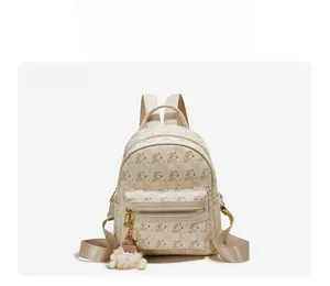 Macro view of beige bear print backpack featuring zipper pocket and sequin plush pendant