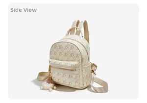 Side view of cream backpack with bear print, gold zippers and white plush sheep charm