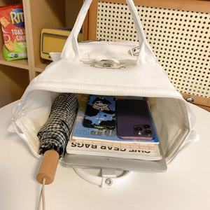 White canvas backpack showing large capacity with laptop, books and daily items