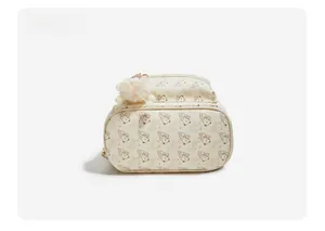 Detailed bottom view of the cream bear pattern backpack with pink plush pom-pom keychain