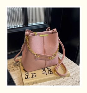 Detailed close-up of pink litchi leather bucket bag with gold chain and strap