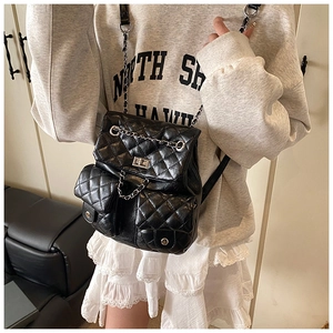 Close-up of black quilted backpack with silver chain straps and front twin pockets
