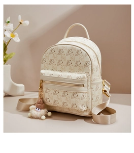 Detail of a beige mini bear print backpack with a plush charm and gold zippers