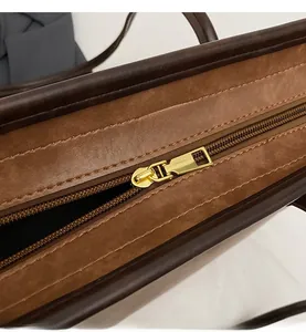 Close-up of smooth gold metal zipper on two-tone brown tote bag with leather texture