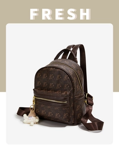 Detailed view of mini brown bear print backpack with gold zipper and plush doll pendant
