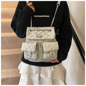 Detail of quilted leather mini backpack featuring dual front pockets and silver chain straps