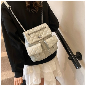 Close-up of quilted chain backpack with turn-lock pockets on model in bright setting