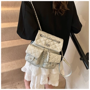 Detail of grey quilted backpack featuring silver twist lock and leather chain straps