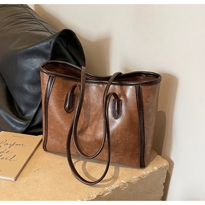 Detail of vintage brown tote bag with dark coffee trim on a rustic stone surface