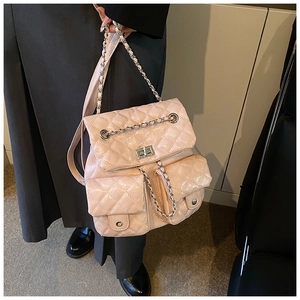 Detail of pink quilted backpack featuring metal chain straps and silver twist-lock closure
