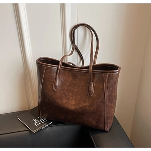 Detail of a dark brown vintage tote bag made of high-quality faux leather with fine straps