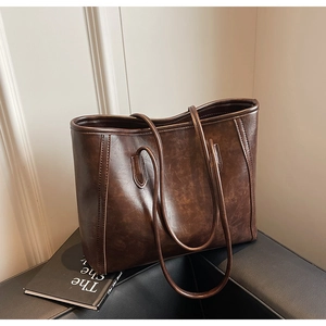 Detail of vintage brown faux leather tote bag showing textured finish and stitching