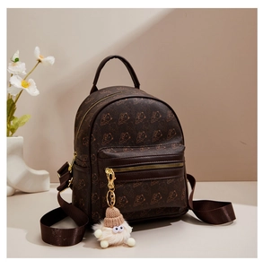 Detail of mini brown backpack with bear print, gold zippers and plush charm