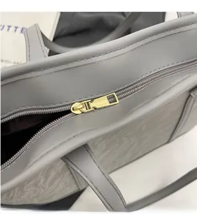Close-up of smooth gold metal zipper and marble pattern texture on a grey tote bag