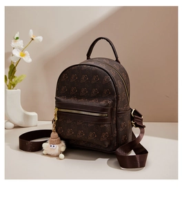 Close-up of brown mini backpack featuring bear prints and a plush charm detail