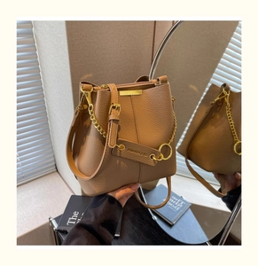 Detail of camel bucket bag with lychee texture leather and gold chain on mirror