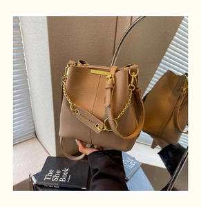 Detail of tan pebble leather bucket bag with gold chain and adjustable strap accents