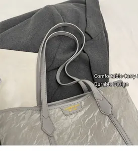Close-up of grey tote bag with unique pleated texture and yellow logo detail