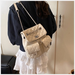 Quilted leather backpack in creamy white with silver chain straps shown on a model