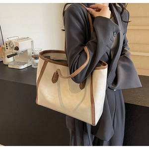 Detail of minimalist tote bag with cream canvas and brown leather handles in a cafe setting