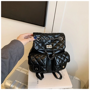 Close-up of black quilted leather backpack with silver chain straps and metal twist-lock