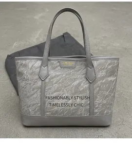 Close-up of grey tote bag with unique wrinkled texture and golden brand logo detail