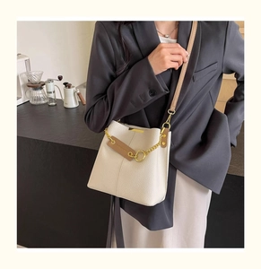 Detail of off-white bucket bag with lychee texture leather and gold chain accent