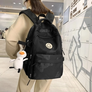 Black nylon backpack with bear pattern and yellow smile logo shown on model's back