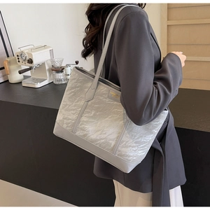 Detail of silver tote bag with pleated texture and reinforced light gray faux leather straps