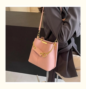 Detailed view of pink bucket bag with lychee texture and gold metal chain strap