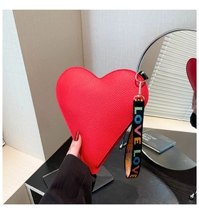 Close-up of red heart-shaped clutch bag with lychee texture and LOVE wrist strap