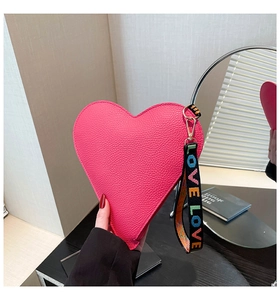 Detail view of heart-shaped coin purse in rose pink litchi grain leather and LOVE strap