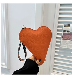 Close-up of orange litchi grain heart-shaped clutch with LOVE printed wrist strap