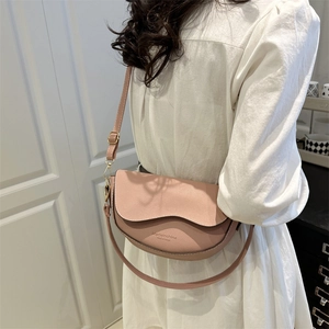 Borsa a sella rosa in pelle martellata con logo oro indossata da modella in bianco