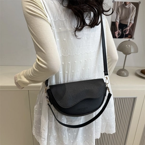 Borsa a sella classica in pelle nera con dettagli dorati indossata da una modella