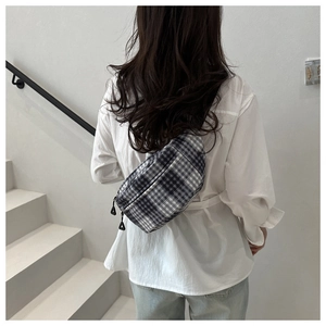 Detail of checkered fanny pack with dual zippers worn as a crossbody bag for men and women
