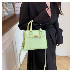 Detail of mint green handbag featuring golden hardware clasp and adjustable strap