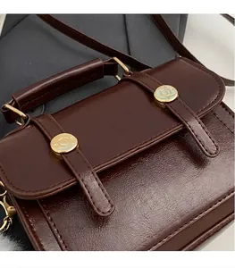 Detailopname van donkerbruine kunstlederen handtas met twee gouden ronde metalen gespen