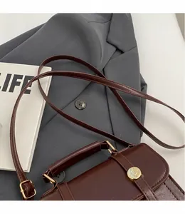 Detail van een vintage donkerbruine crossbodytas met een gladde verstelbare schouderriem