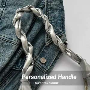 Detail of silver woven handle with decorative knot and metal zipper on a fashion bag