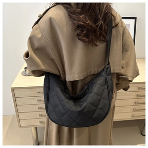 Détail du sac à bandoulière en croissant noir matelassé montrant le tissu en nylon