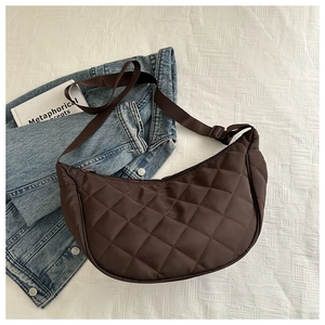 Detail of dark brown quilted crescent bag with adjustable nylon strap and metal zipper