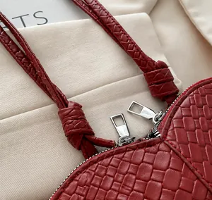Detail of red woven leather handbag featuring silver double zippers and braided handles