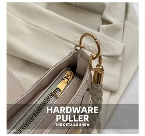 Detailaufnahme der cremefarbenen Tasche mit goldenem Reißverschluss und Webgriff