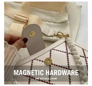Detail des Metall-Magnetverschlusses an weißer gesteppter Ledertasche mit Trageriemen