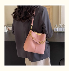 Close-up of pink bucket bag featuring lychee grain leather and golden chain hardware details