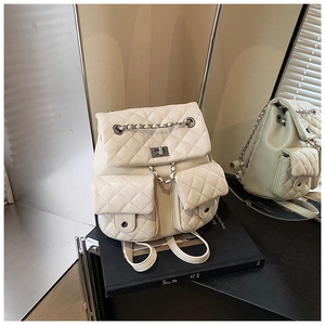 Detailed close-up of quilted cream backpack with chain straps and metal twist locks