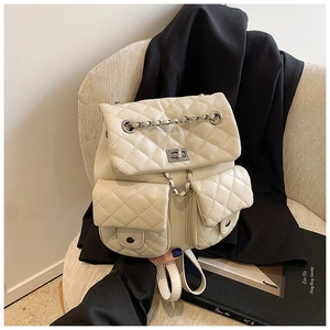 Detail of beige quilted mini backpack featuring metal turn-lock and chain straps