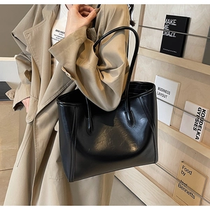 Detailed view of black large-capacity tote bag with fine leather texture on model