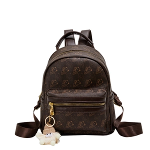 Brown leather backpack with bear print, gold zippers and a plush charm on white background